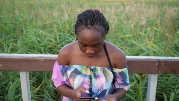 Feliz señora afroamericana con saltos de teléfono cerca de pasamanos — Vídeo de stock