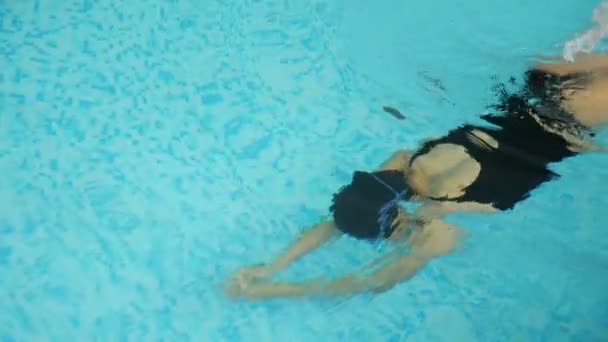 Donna graziosa si tuffa e nuota all'interno di acqua limpida piscina — Video Stock