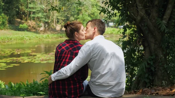 Mladý muž sedí v blízkosti tmavé vlasy žena a objetí s láskou — Stock fotografie