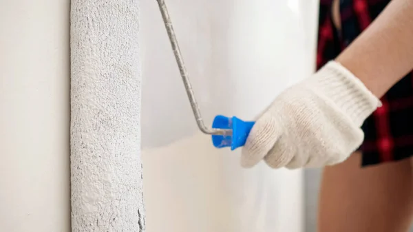 Mujer en guantes pinta la pared en color gris claro con rodillo — Foto de Stock