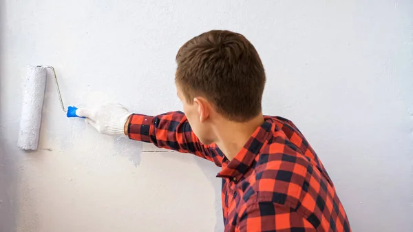 Τύπος ζωγραφίζει τοίχο σε γκρι κάνοντας επισκευή σε ευρύχωρη βεράντα — Φωτογραφία Αρχείου