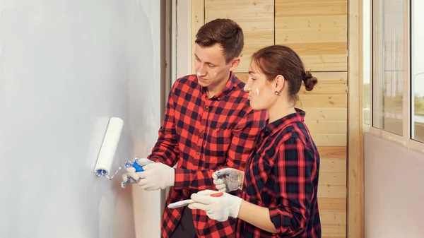 Usmívající se žena pomáhá manžel malovat stěnu na lehké terase — Stock fotografie