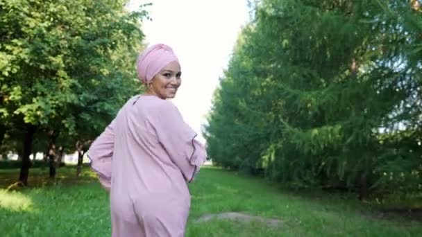 Chica atlética en vestido púrpura y hijab corre a lo largo del camino — Vídeos de Stock