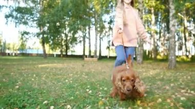 Kız yeşil parkta koşuyor elinde komik bir kızıl köpek tasmasıyla