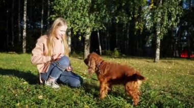 Sarı saçlı kız gülümseyip Rus köpek ile oynuyor.