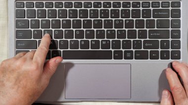 Dizüstü bilgisayarda yazan yaşlı bir kadının klavyesi ve elleri.