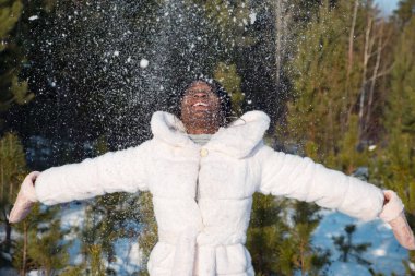 Koyu tenli kadın soğuk bir öğleden sonra karla oynuyor.
