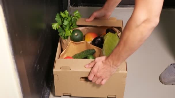 Dostawca stawia papierowe pudełko z warzywami na białej podłodze — Wideo stockowe
