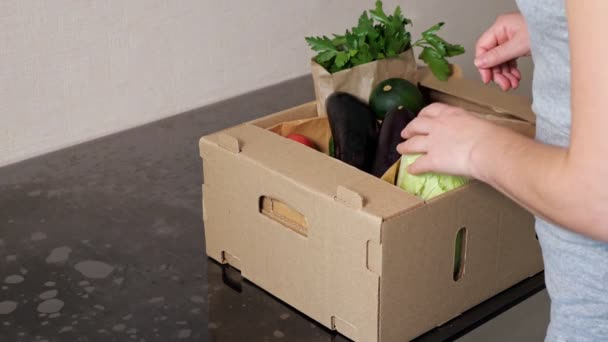 Femme approche boîte brune et prend des légumes commandés — Video