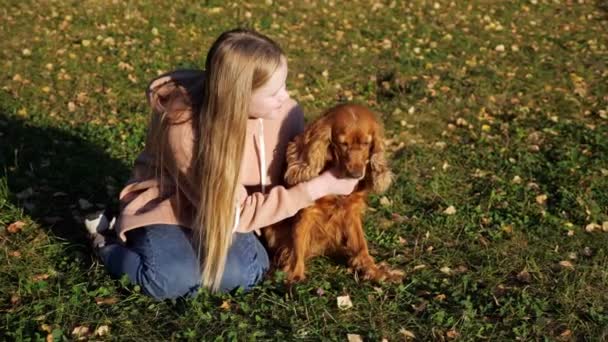 Chica sonriente en sudadera con capucha rosa y jeans mascotas perro jengibre — Vídeos de Stock