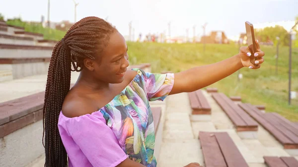 Afro-americana dama en elegante blusa hace selfie en parque —  Fotos de Stock