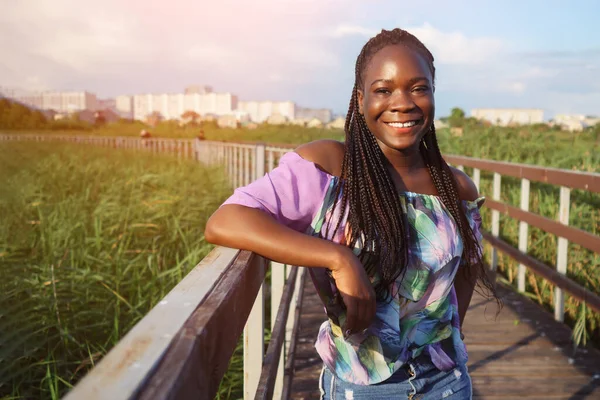 Ung afrikansk amerikansk kvinna står på bron och ler — Stockfoto