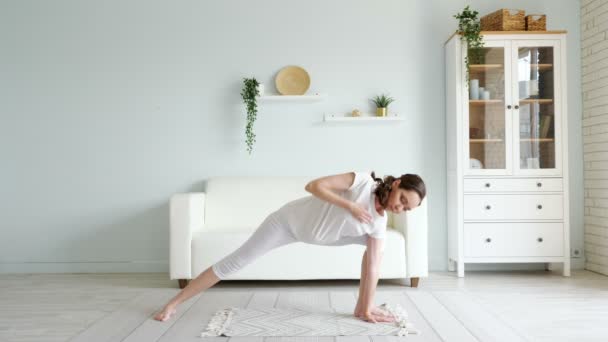 Zwangere vrouw doet utthita parsvakonasana op de vloer thuis — Stockvideo