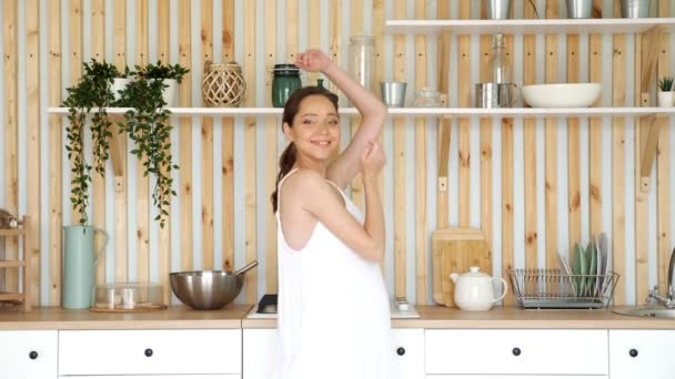 Радостные танцы беременной женщины на современной дизайнерской кухне — стоковое видео