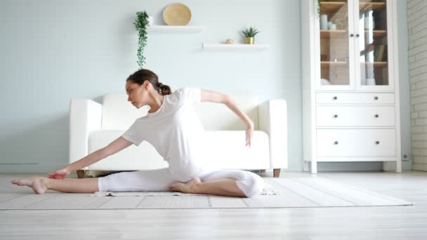 Femme enceinte ne janu sirsasana assis sur le sol près du canapé — Video