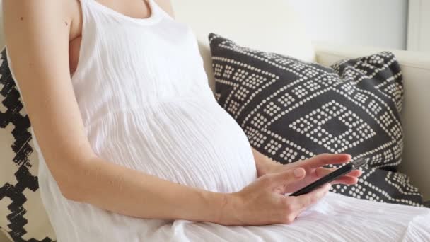 Lady incinta naviga su internet con smartphone seduto sul divano — Video Stock