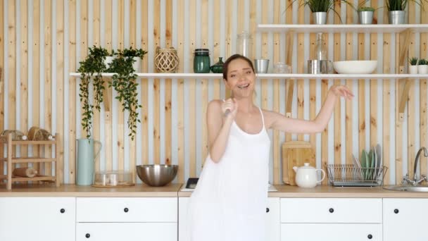 Gravid kvinna dansar och sjunger med visp i köket — Stockvideo