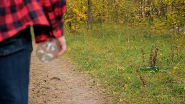 Nerozpoznatelný muž hodí plastovou láhev do trávy zpomaleným pohybem v lese — Stock video