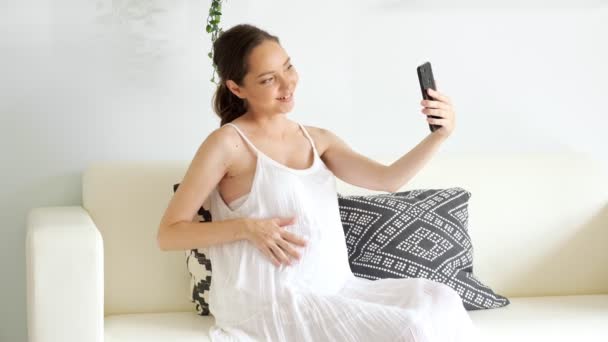 Donna incinta ha videocall con smartphone seduto sul divano — Video Stock