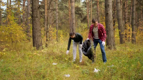 Άντρας και γυναίκα με γάντια συλλέγουν σκουπίδια στο δάσος. — Αρχείο Βίντεο