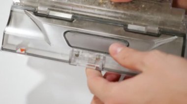 Adam robot elektrik süpürgesi kutusundan çöp döküyor.