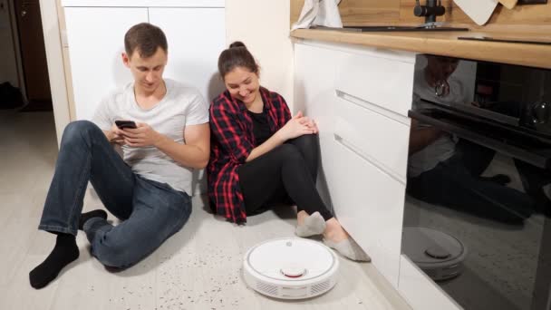 Family controls robot vacuum cleaner operation with phone — Stock Video