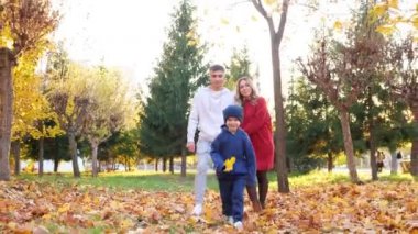 Küçük oğlu sonbahar parkı boyunca anne ve babasının önünde koşuyor.