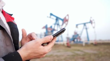 Üniformalı bir erkeğin yakın plan fotoğrafı. Arka planda petrol pompası olan bir telefon var.