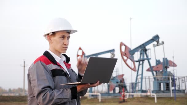 Tipos de ingenieros en una computadora portátil cerca de derrick aceite — Vídeo de stock