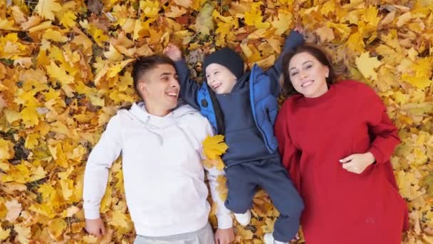 Madre padre y niño pasar tiempo acostado en hojas amarillas — Vídeo de stock