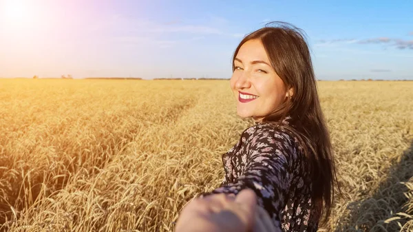 Mulher morena leva através de um campo de trigo maduro girando sorrindo — Fotografia de Stock