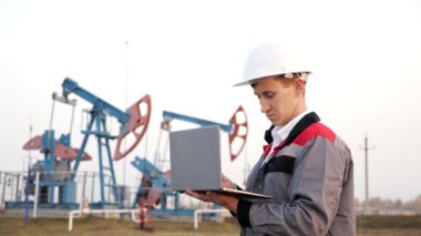 Petrol pompasının arka planında dizüstü bilgisayarı olan petrol endüstrisi mühendisi.