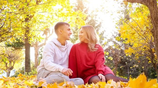 Paar auf dem Boden sitzend und einander an einem warmen Herbsttag anschauend — Stockfoto