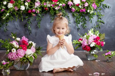 Küçük kız dondurma ve gülüyor yiyor. Bir çiçek dekor bir iç. Duygusal güzel kız portresi