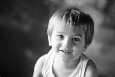 Küçük çocuk portresi. Çocuk 3-4 yıl kameraya bakarak gülümsüyordu. Duygusal portre kapatın. Siyah beyaz resim