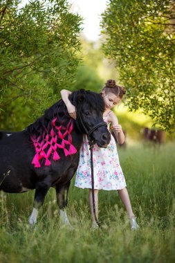 Sevimli küçük kız parkta siyah midilli ile