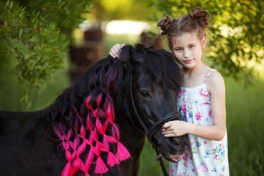 Sevimli küçük kız parkta siyah midilli ile