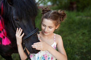 Sevimli küçük kız parkta siyah midilli ile. Resmi kapatmak