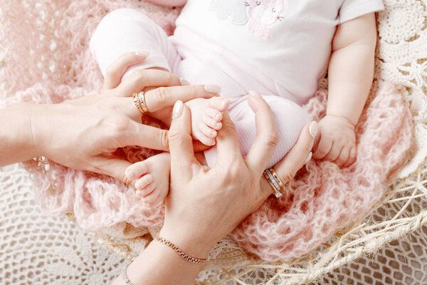 Newborn baby feet in mother hands. Mother holding legs of the kid in hands. Close up image. Happy family concept.