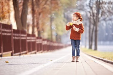 Güzel küçük kız ve sonbahar parkında sabun köpükleri. Sabun köpüğü üfleyen güzel küçük kızın portresi.