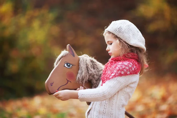 Милая Маленькая Девочка Кормит Деревянную Игрушечную Лошадь Осеннем Саду — стоковое фото