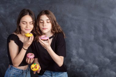 Mutlu oldukça genç kızlar eğleniyor çörek ile. Siyah arka plan üzerine çörek ile neşeli kız portresi. İyi bir ruh hali, diyet kavramı.