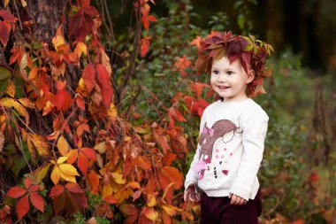Küçük kız sonbahar duygusal portre. Sonbahar Park kırmızı üzüm yaprakları ile sevimli küçük kız. Çocuklar için sonbahar aktivitelere. Aile için Cadılar Bayramı ve Şükran zaman eğlenceli.