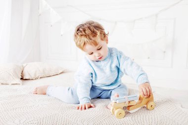 Çocuk çocuk odasında bir ahşap oyuncak araba ile oynamak.