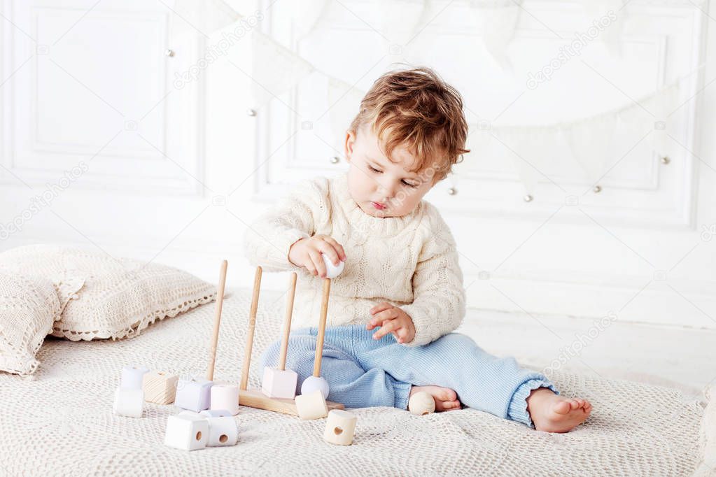 Child boy playing in his room with a wooden toy sorter 
