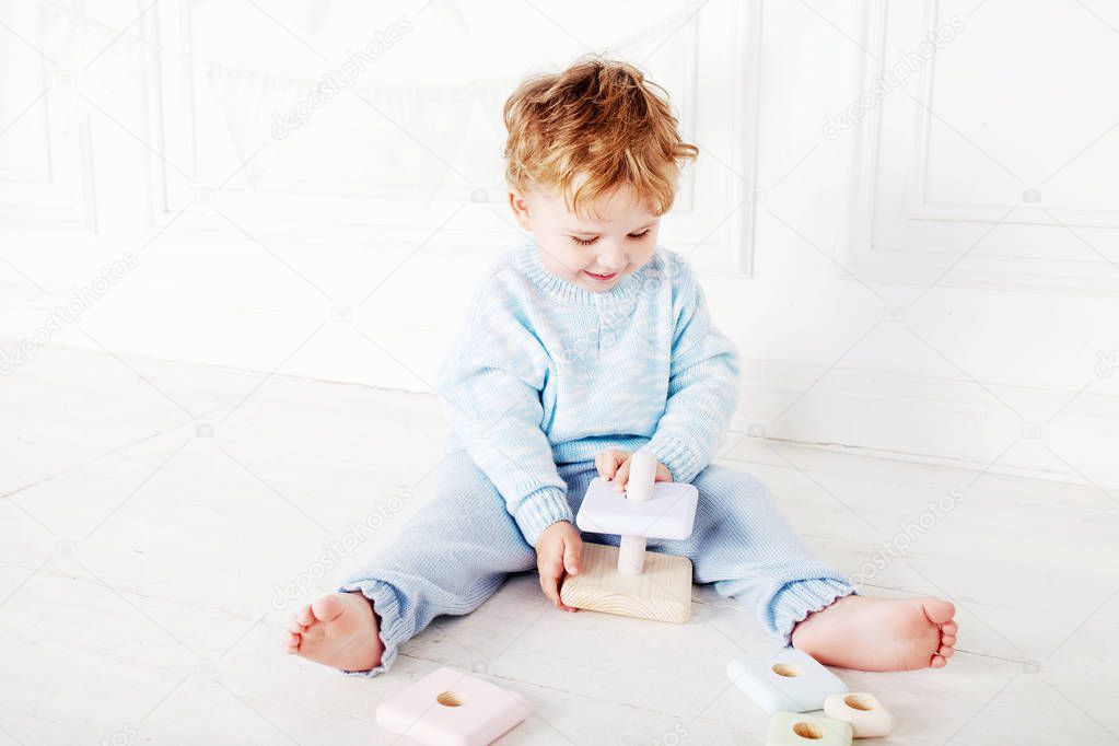 Child boy playing in his room with a wooden toy pyramid. Smiling cute boy with  natural toys. 