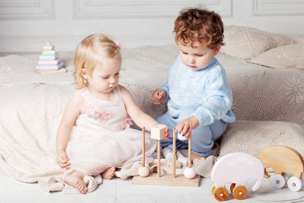 Small children playing together with a wooden toy sorter.  Little boy and girl with natural toys.