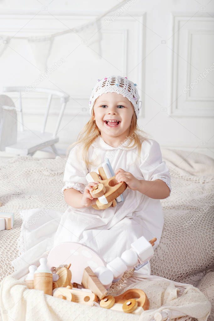 Smiling child girl playing with a wooden toys. Little cute girl with  natural toys.  