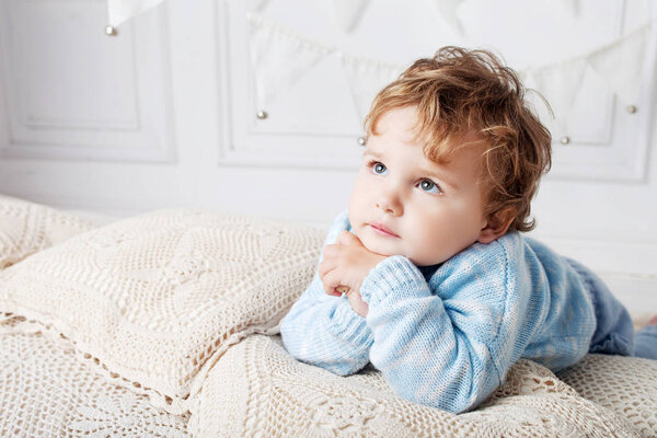 Portrait of happy adorable baby boy on the bed in his room. Copy space