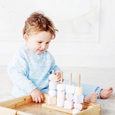Çocuk çocuk odasında bir ahşap oyuncak sıralayıcısı ile oynarken. Doğal oyuncaklar ile gülümseyen sevimli çocuk. 
